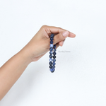 Hand holding a original sodalite blue beaded bracelet against a white background