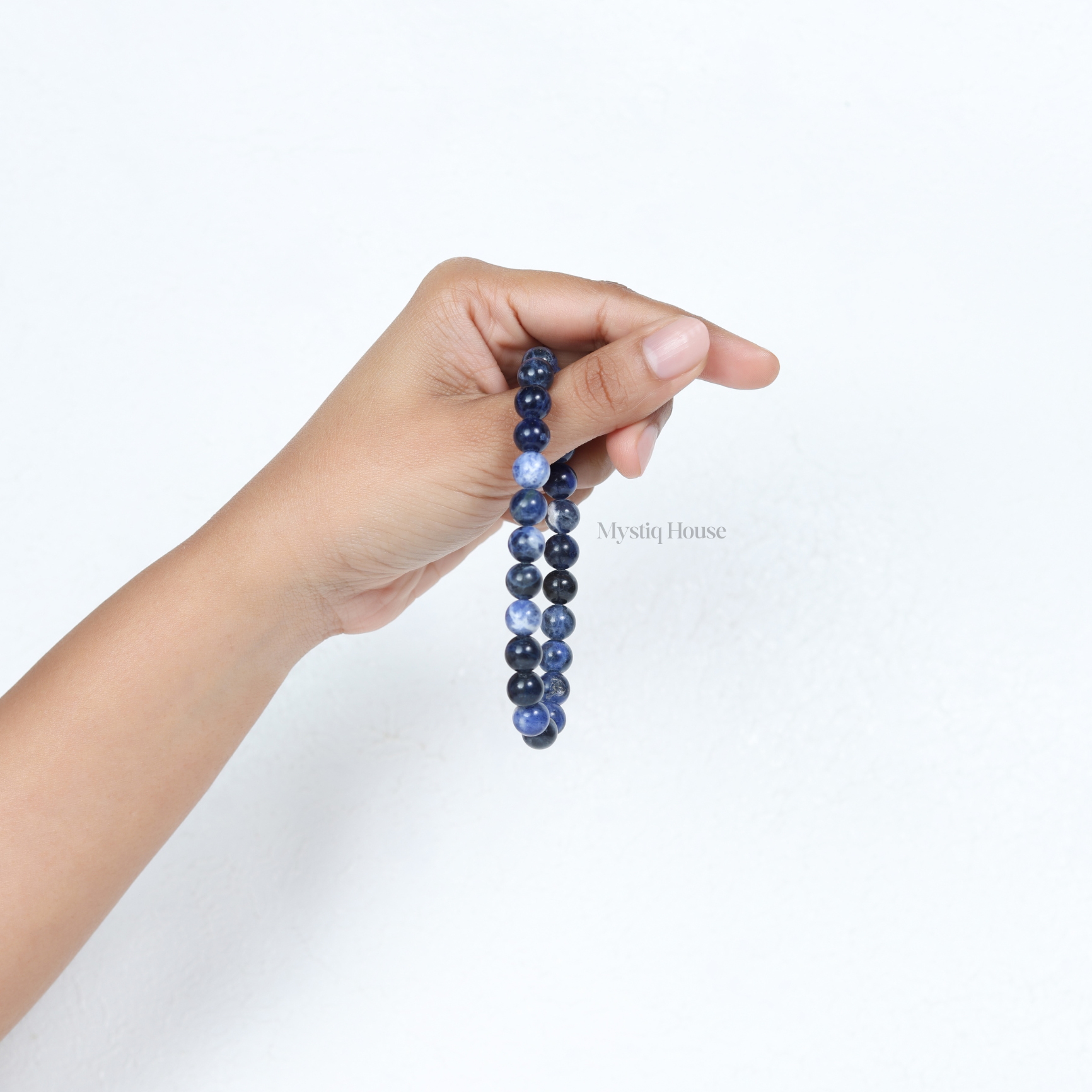 Hand holding a original sodalite blue beaded bracelet against a white background