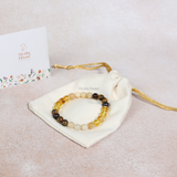 Beaded bracelet on a white drawstring bag with 'Mystic House' branding, on a light beige background.