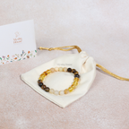Beaded bracelet on a white drawstring bag with 'Mystic House' branding, on a light beige background.