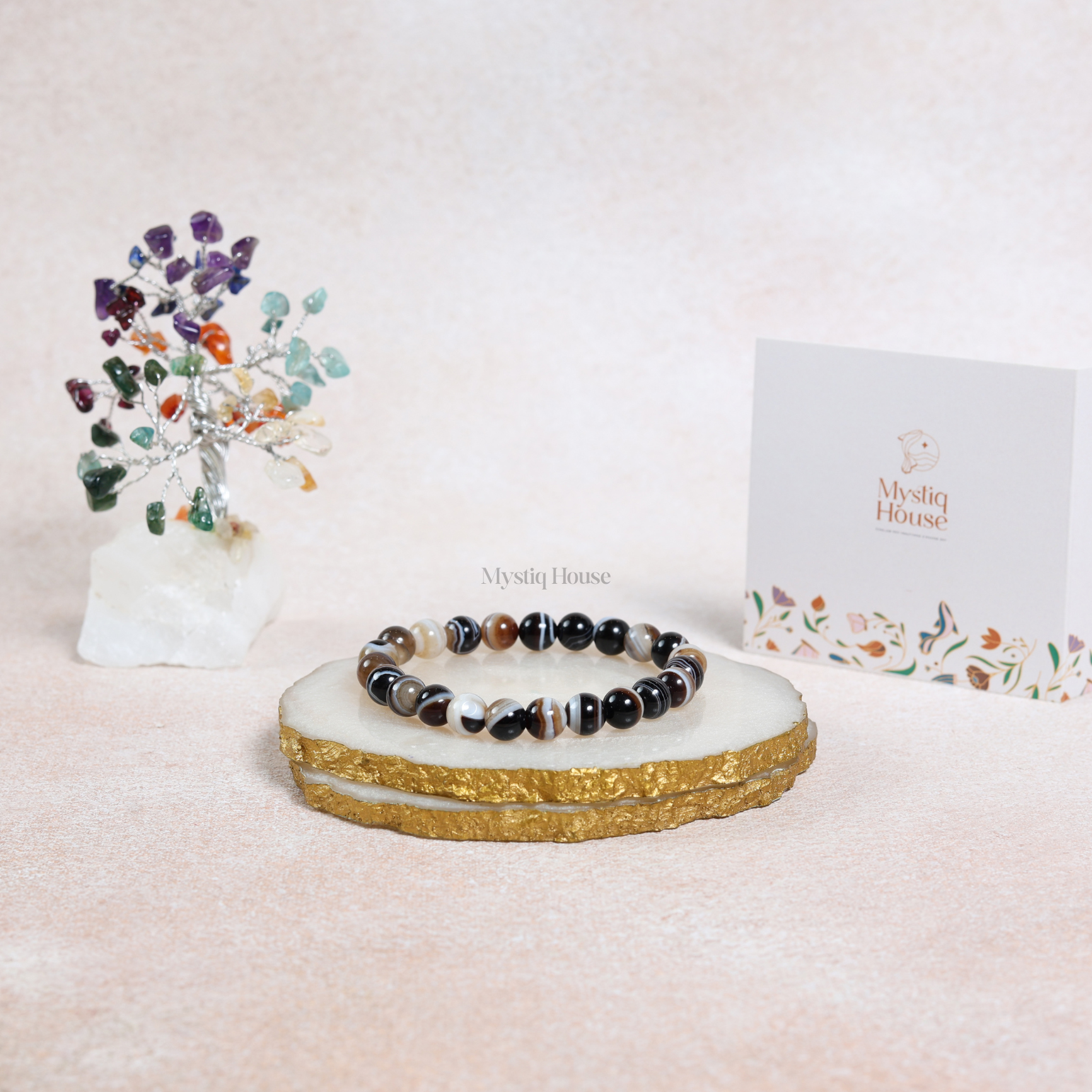 Bracelet on a decorative stand with a 7 chakra crystal tree and Mystiq House card in the background